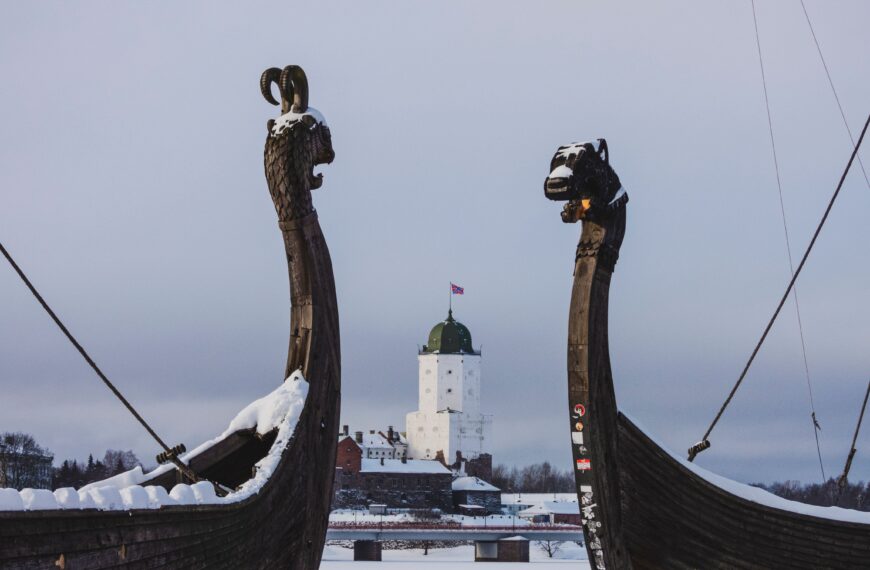 Depicts Viking ship replicas with a snow-covered medieval castle in the background.