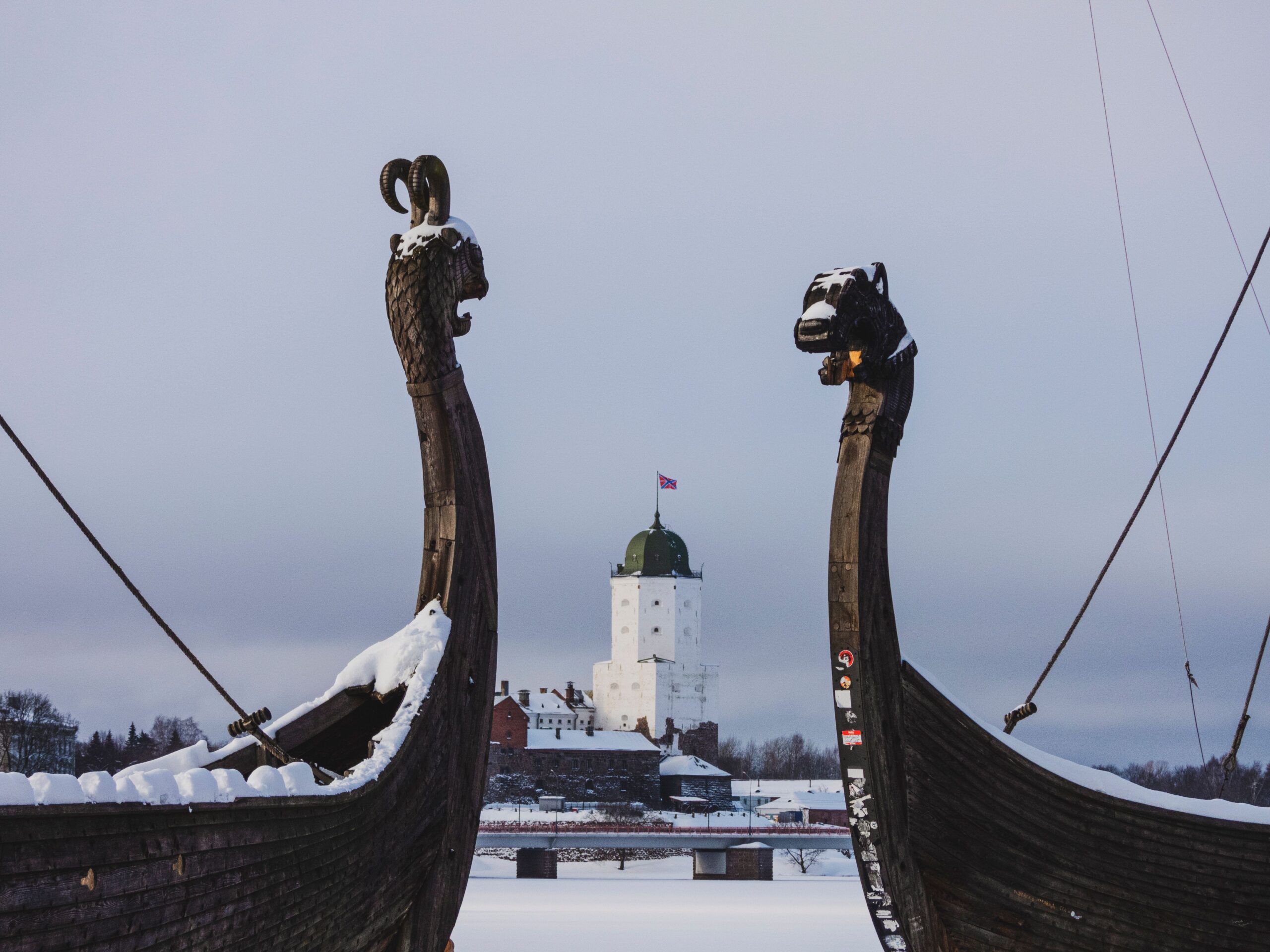 Depicts Viking ship replicas with a snow-covered medieval castle in the background.