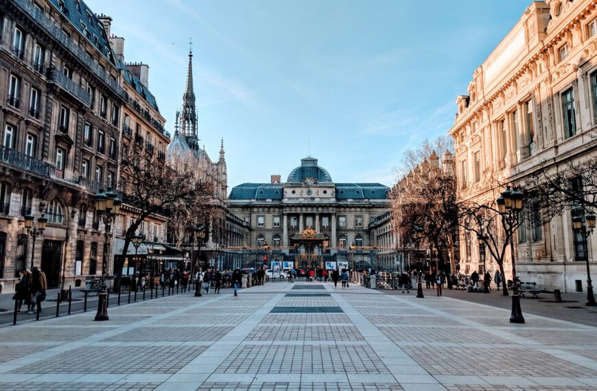 A vibrant street view of Paris featuring the Palace of Justice with a clear blue sky.