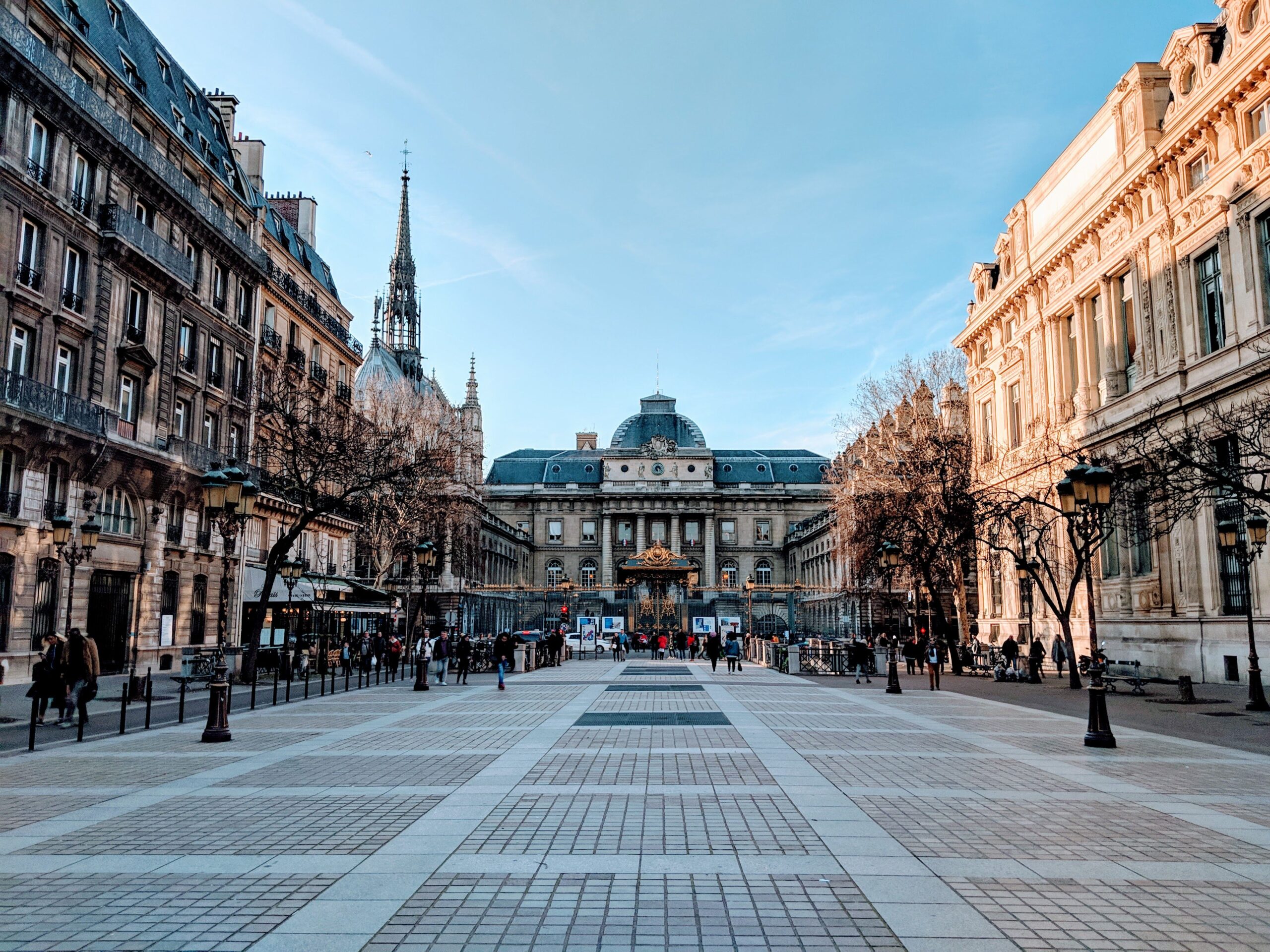 A vibrant street view of Paris featuring the Palace of Justice with a clear blue sky.