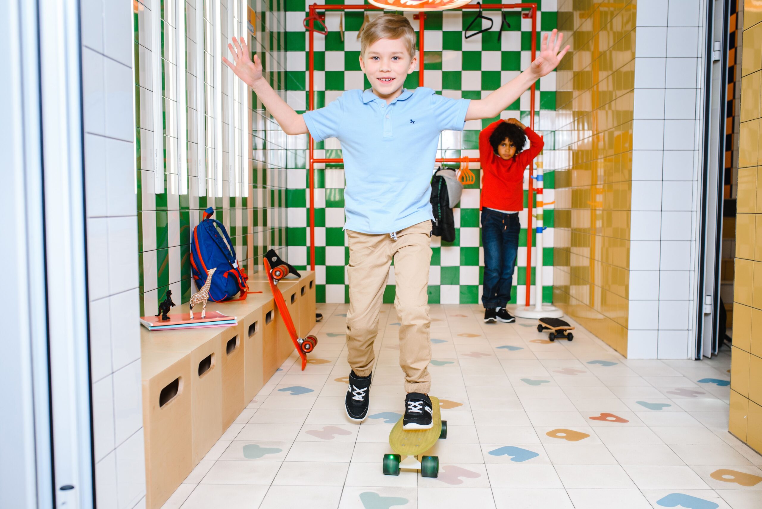 Two kids skateboarding inside a tiled room, enjoying fun activities.
