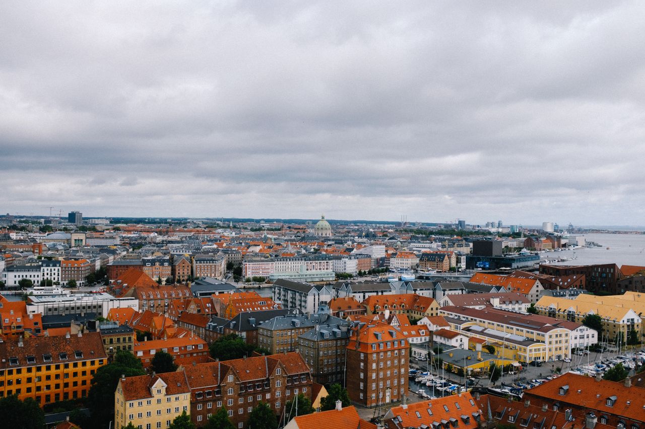 A stunning aerial view of Copenhagen's colorful cityscape under overcast skies, featuring iconic landmarks.