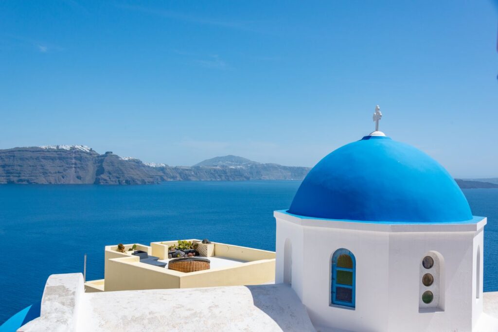 Ikonisk kirke med blå kuppel på Santorini med en fantastisk udsigt over Det Ægæiske Hav.
