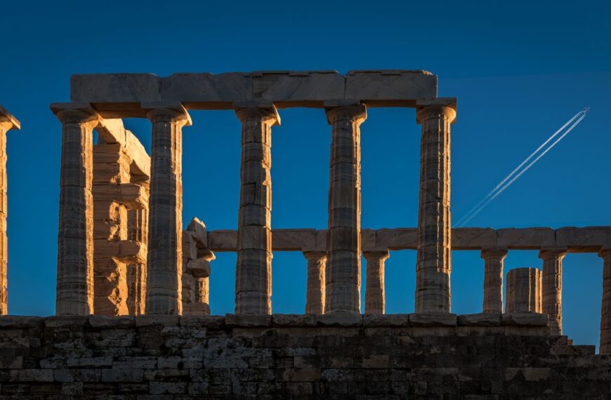 Explore the stunning Temple of Poseidon ruins at Cape Sounio against a clear blue sky.