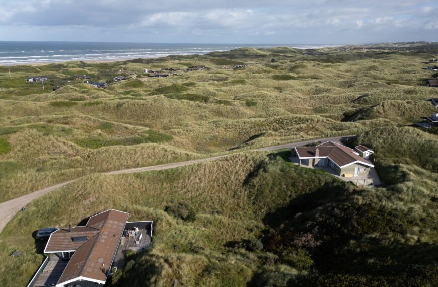 Explore the serene dunes and coastal homes in Saltum, Denmark, captured from above with a focus on nature.