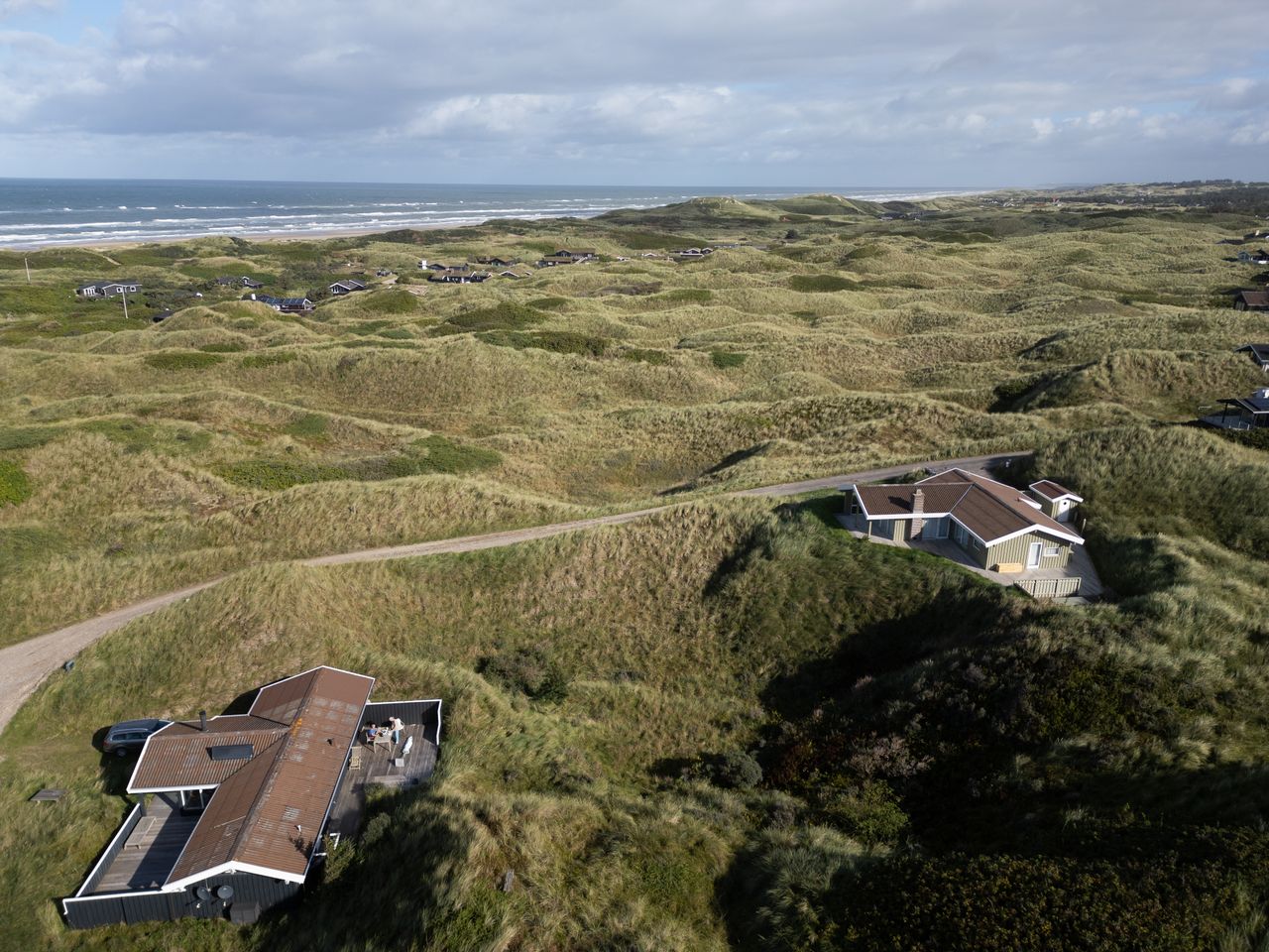 Explore the serene dunes and coastal homes in Saltum, Denmark, captured from above with a focus on nature.