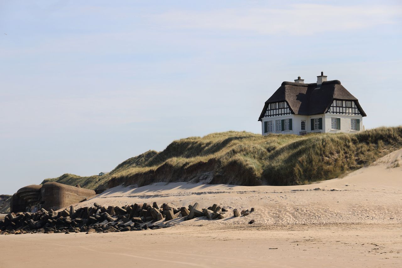 Scenic view of a beach house on dunes in Løkken, Denmark, on a sunny day.