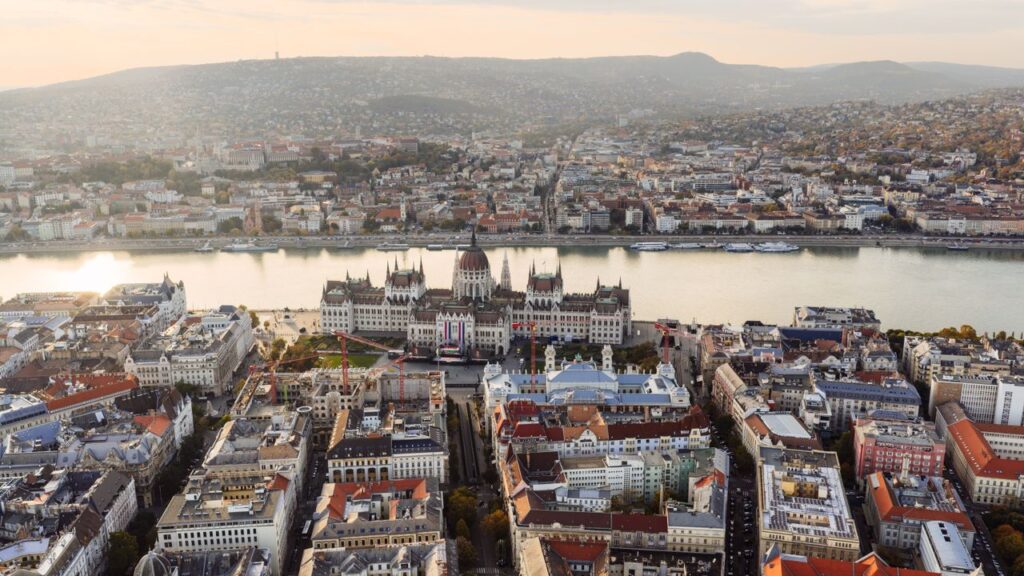 Fantastisk luftfoto af Budapest med den ikoniske ungarske parlamentsbygning langs Donau ved solnedgang