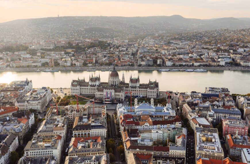 Stunning aerial view of Budapest featuring the iconic Hungarian Parliament Building along the Danube River at sunset.