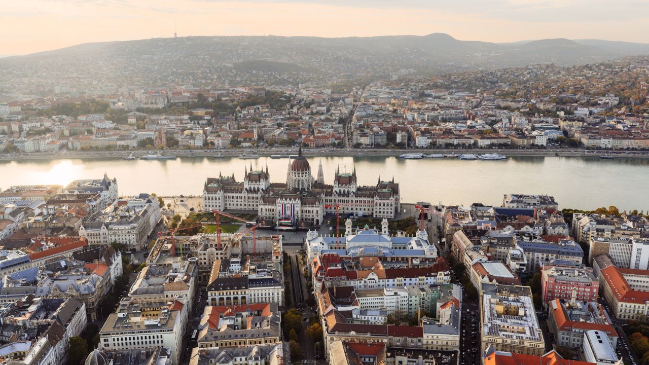 Stunning aerial view of Budapest featuring the iconic Hungarian Parliament Building along the Danube River at sunset.