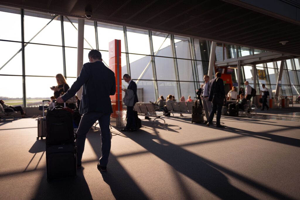 Rejsende med håndbagage venter på afgang i en travl lufthavnsterminal