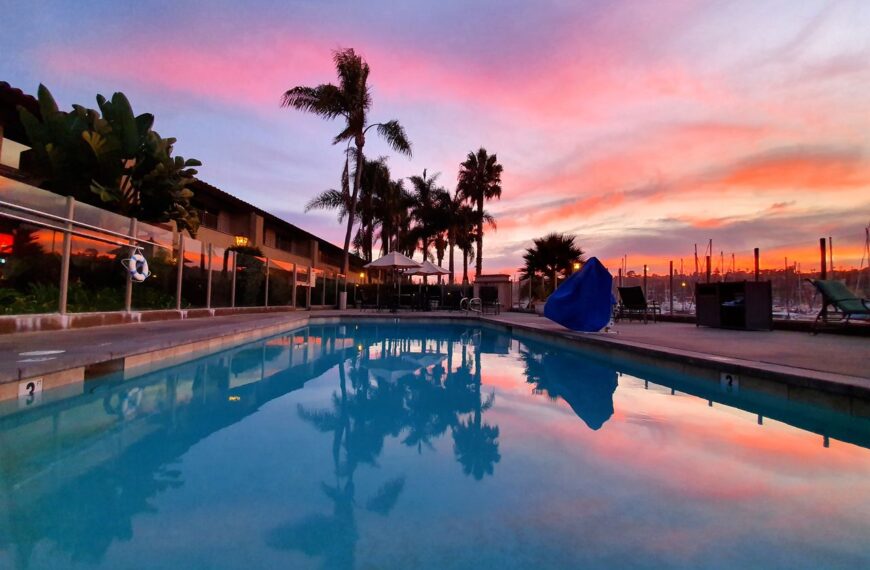 Poolside view with palm trees during a vibrant sunset in San Diego.