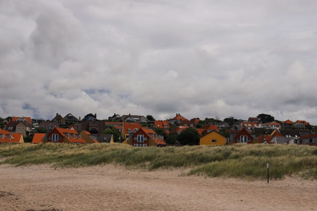 Malerisk udsigt over farverige huse langs sandstranden i Hundested, Danmark.