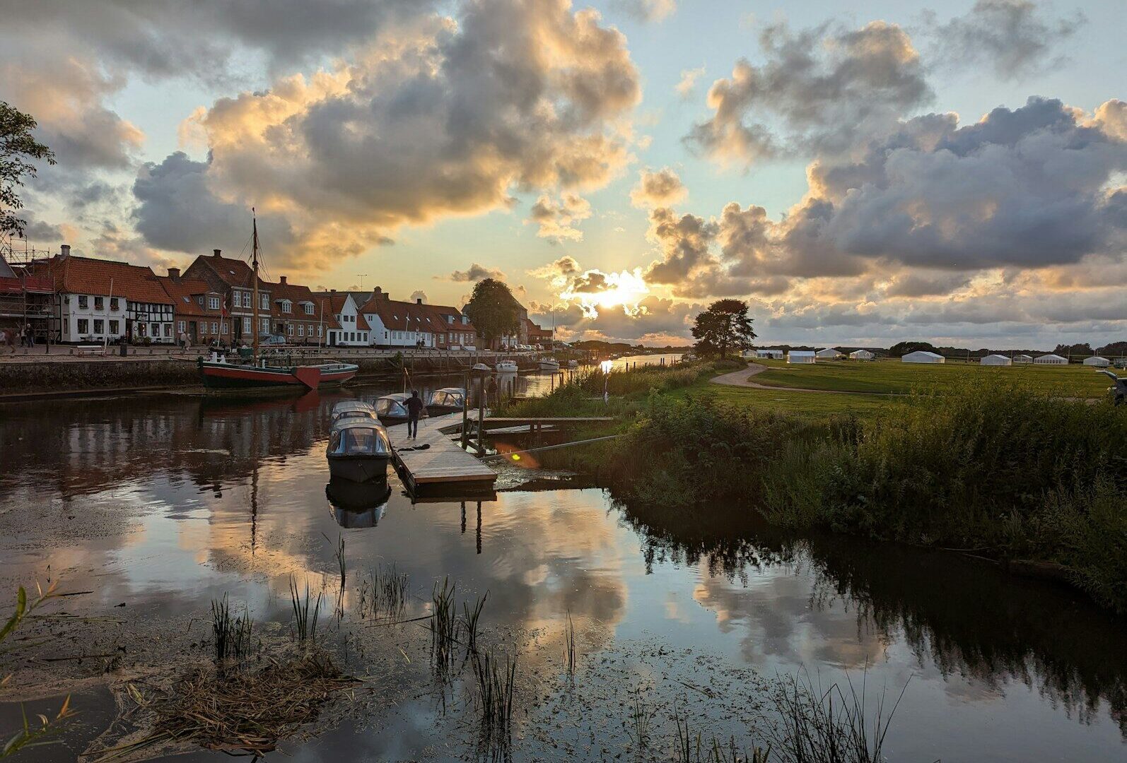 Både og huse ved Ribe Å under en skyet aftenhimmel