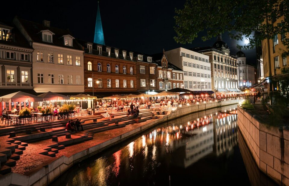 Oplyste caféer og historiske bygninger langs Aarhus Å om aftenen