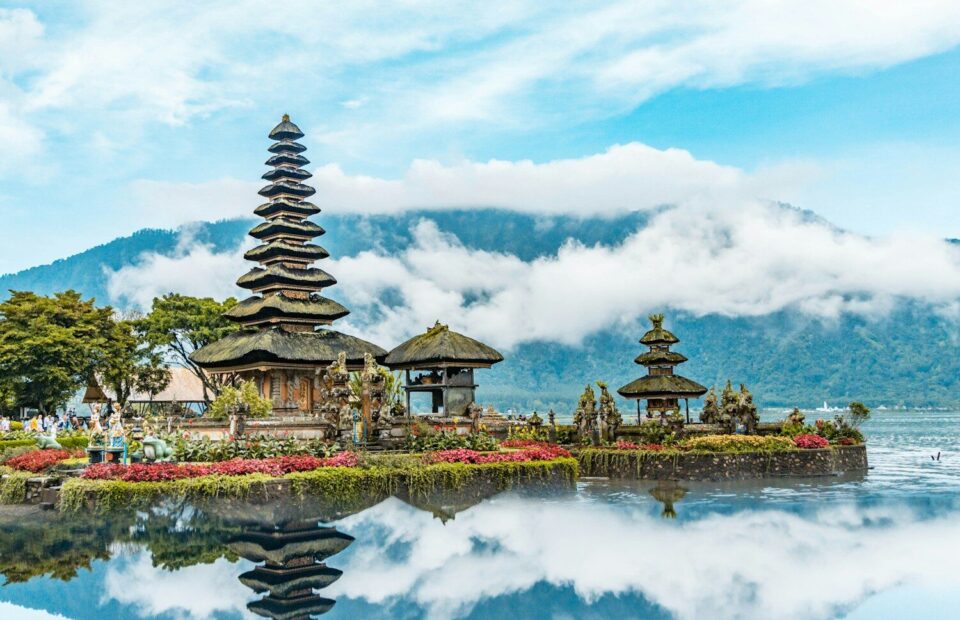 brown and green temple near body of water under blue and white cloudy sky during daytime