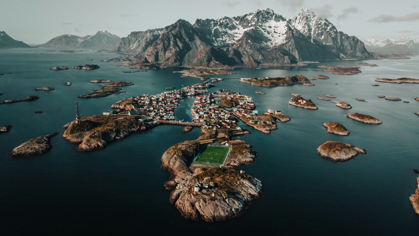 Henningsvær i Lofoten set fra luften med små øer, havn og bjerge