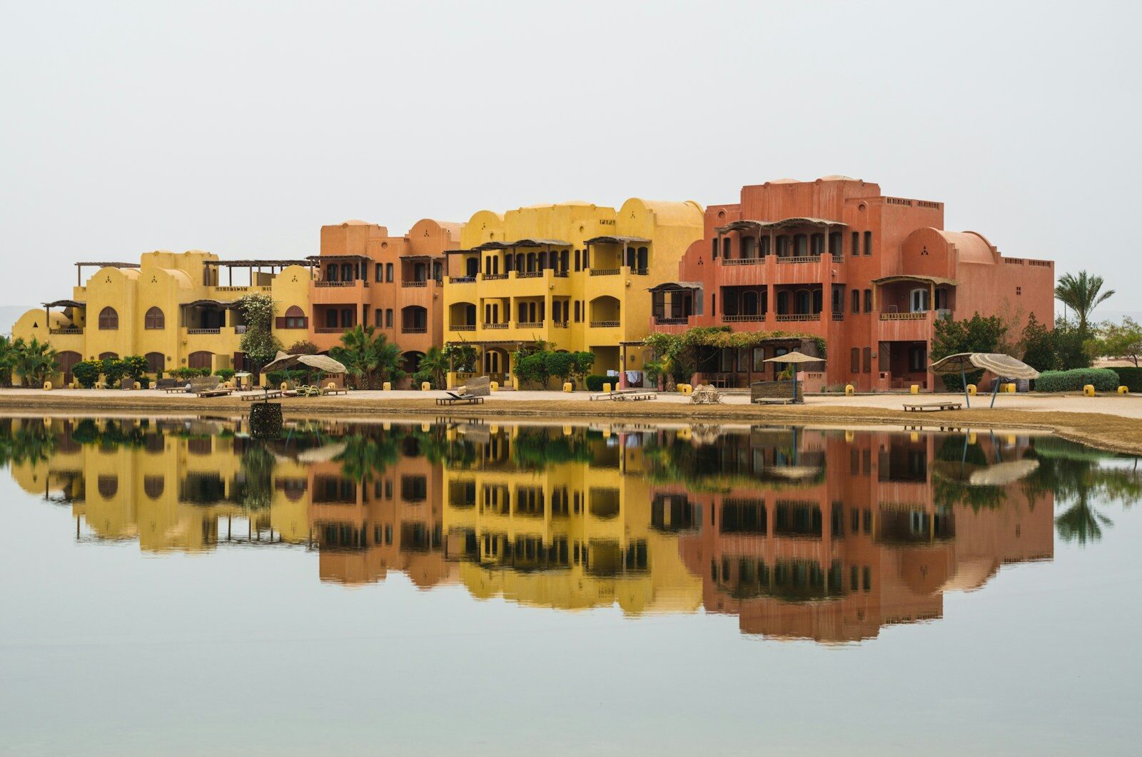 Gule og orange bygninger med palmer, der spejler sig i en lagune i El Gouna