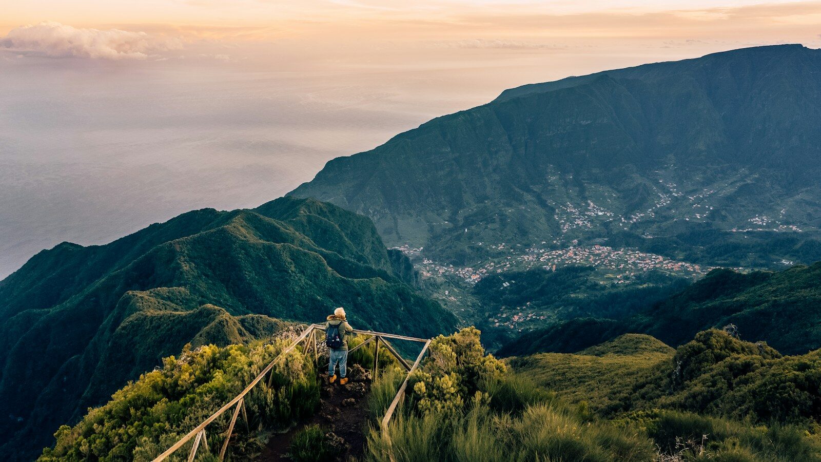 Vandrer på en bjergsti med rækværk og udsigt over grønne bjerge på Madeira