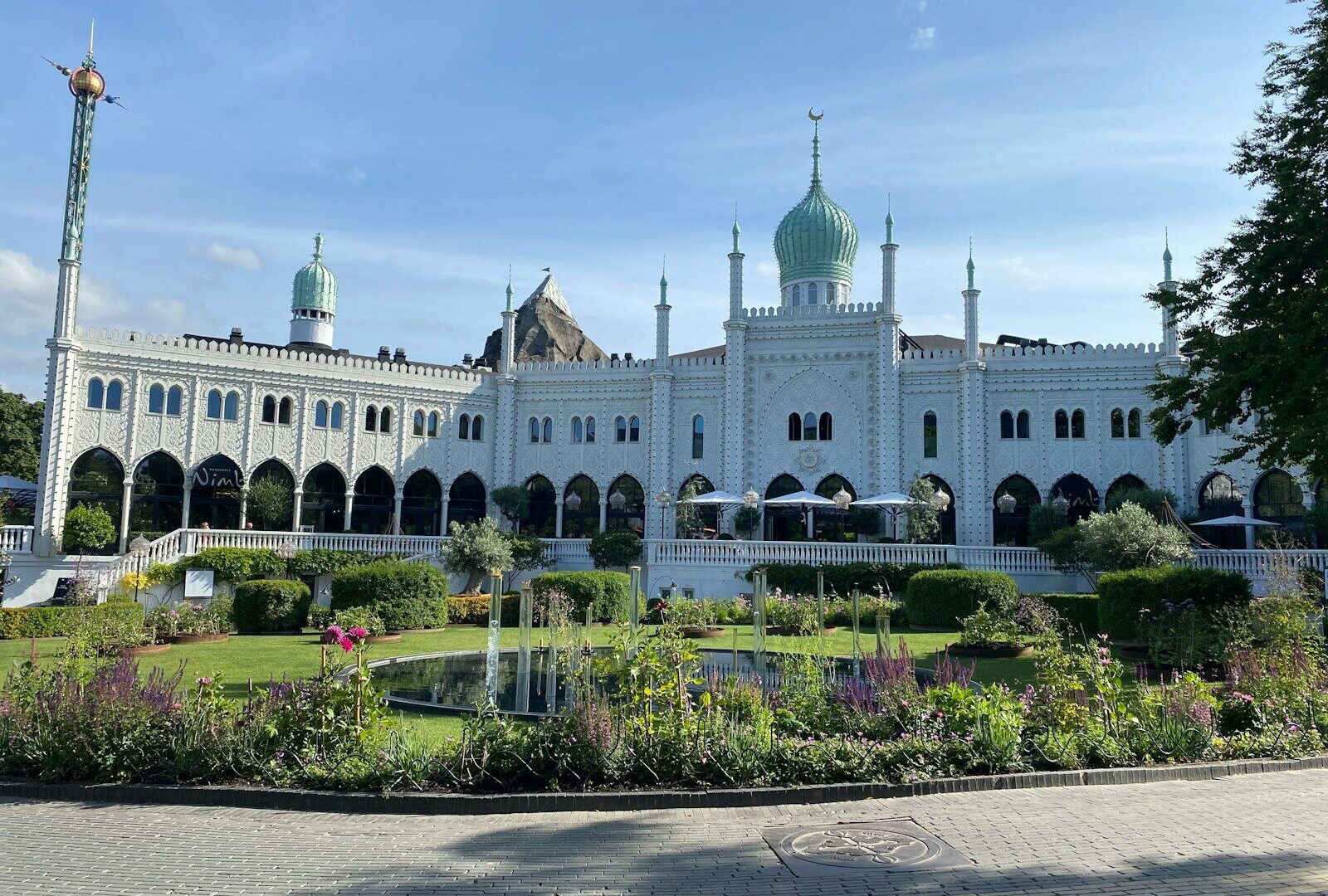 Nimbs hvide facade med grønne kupler set fra haven i Tivoli