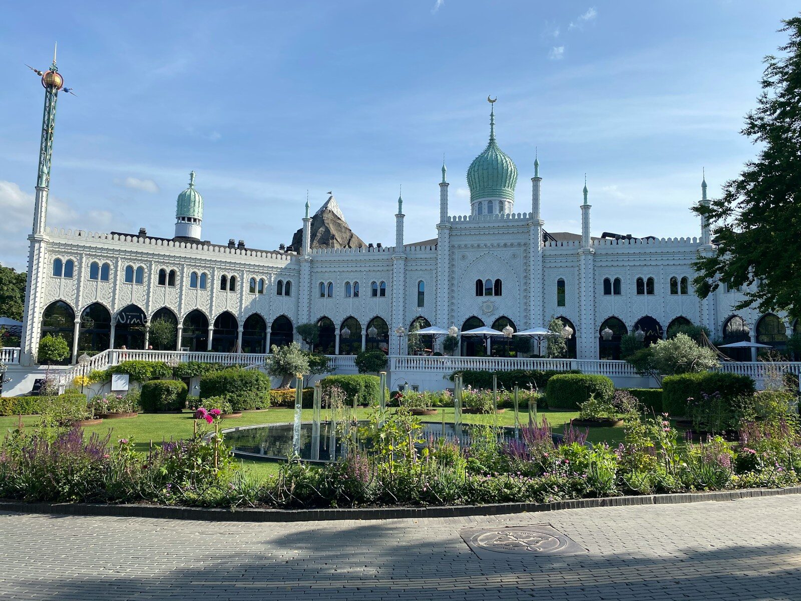 Nimbs hvide facade med grønne kupler set fra haven i Tivoli