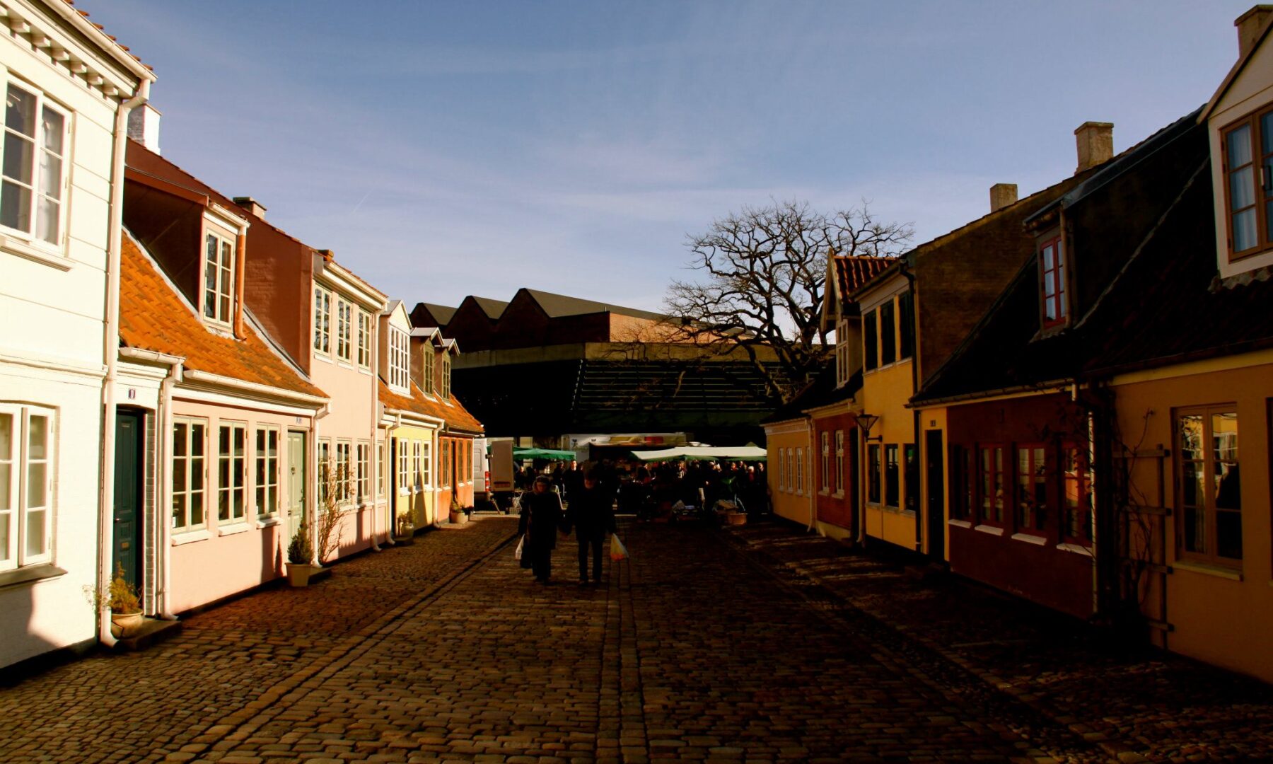 Sne langs en brostensgade med lave, farverige huse i Odense