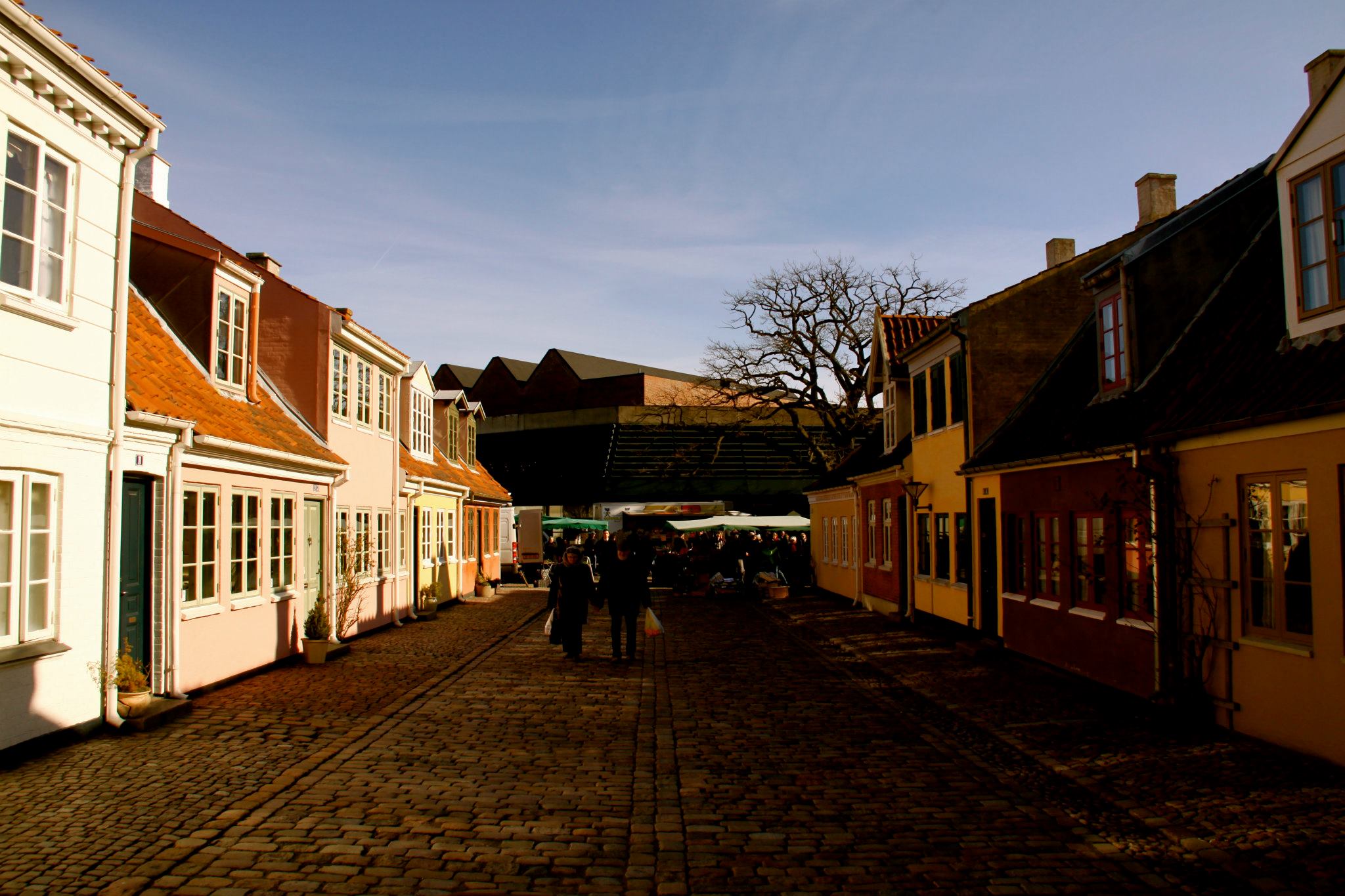 Sne langs en brostensgade med lave, farverige huse i Odense