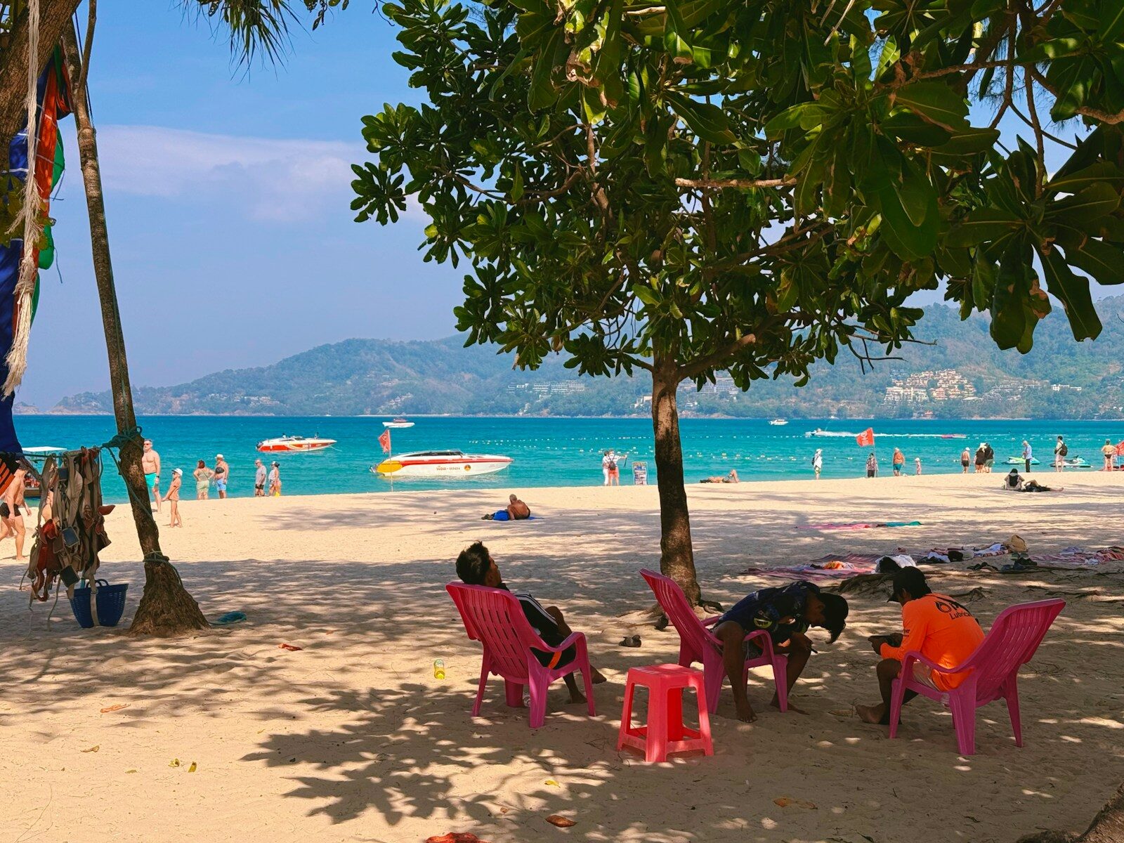 Palmer og røde stole ved en sandstrand med turkisblåt hav på Phuket