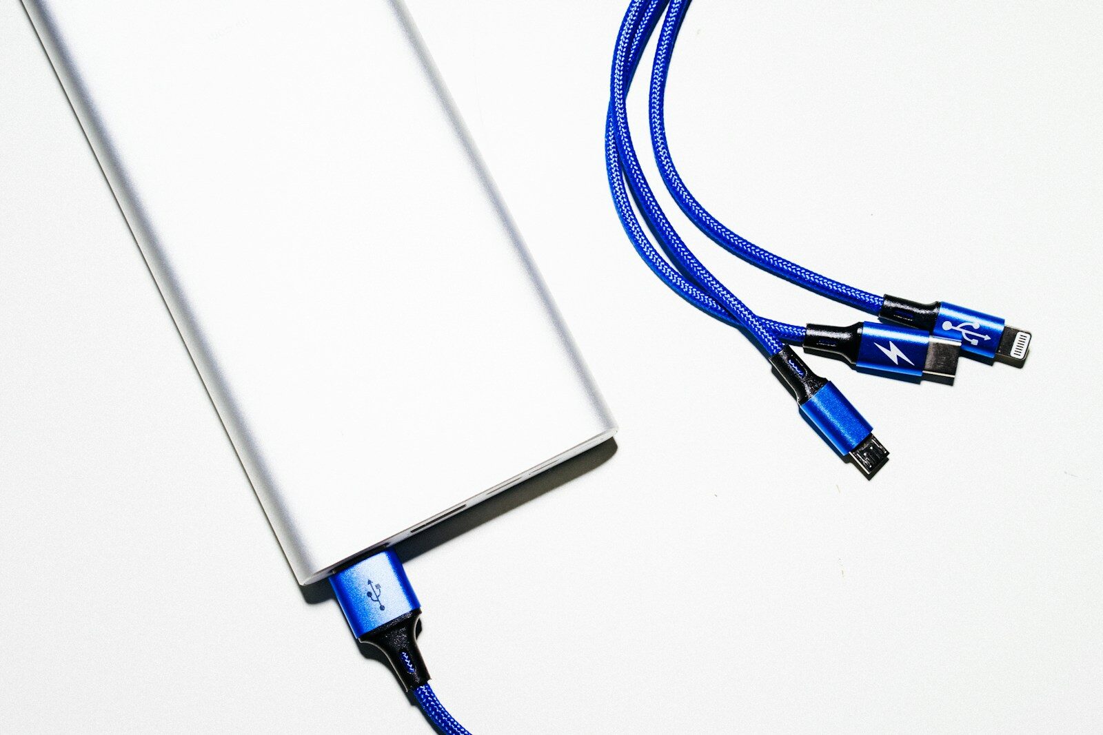 Lys powerbank med et blåt ladekabel og flere stik på hvid baggrund