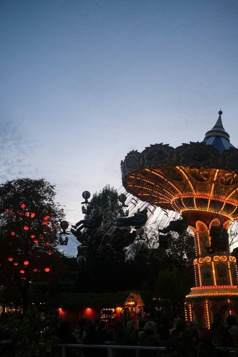 Oplyst karrusel og forlystelser i Tivoli i skumringen