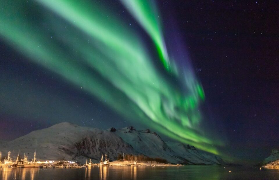 Grønt nordlys over fjeld og fjord ved Ersfjord nær Tromsø i Norge